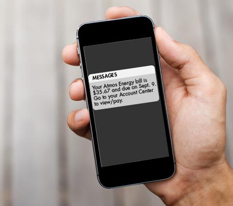 hand holding smartphone displaying text message from Atmos Energy