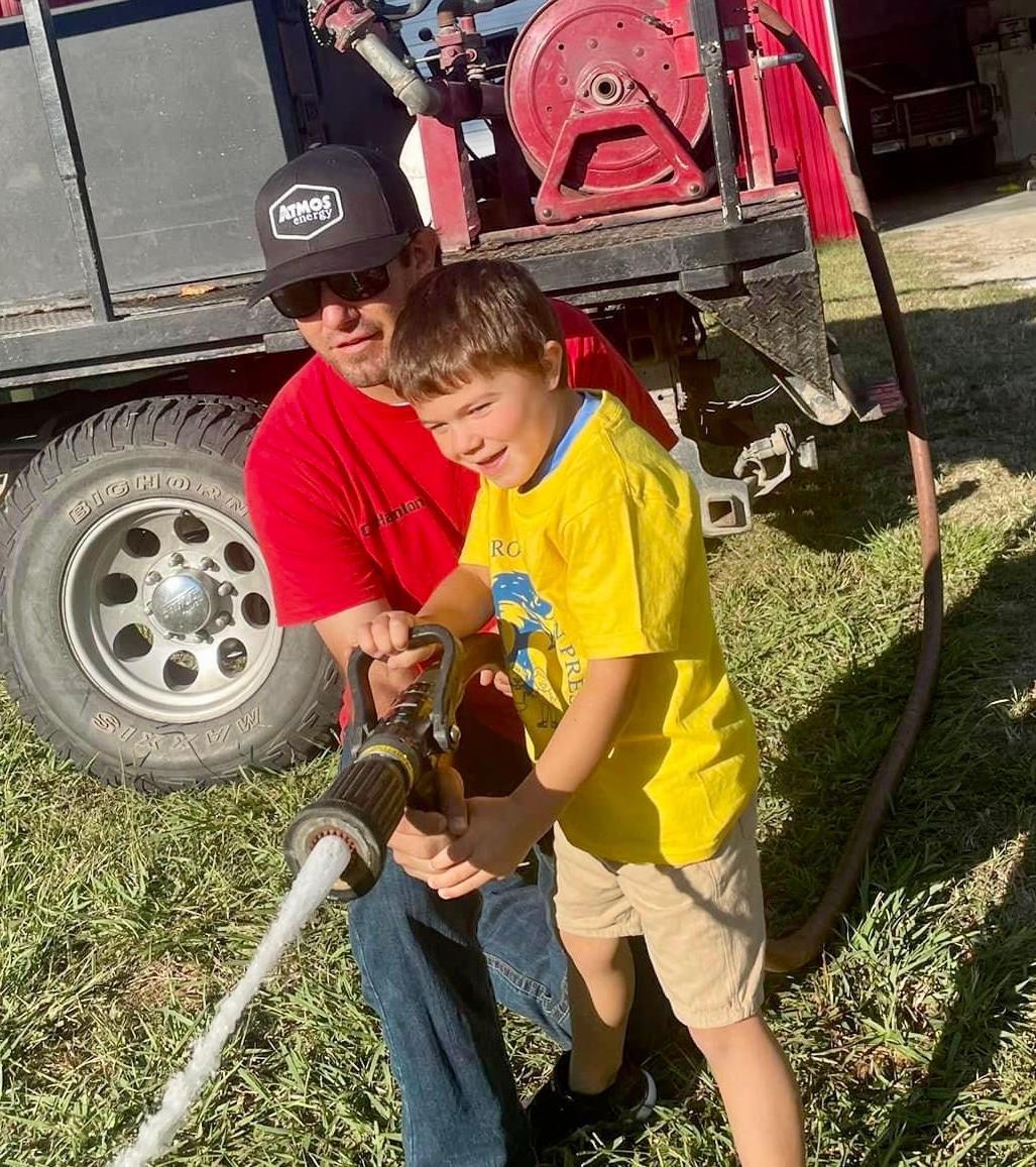 Casey Hanlon and his son, Tripp, douse an imaginary blaze during fire prevention week at Tripp’s school.