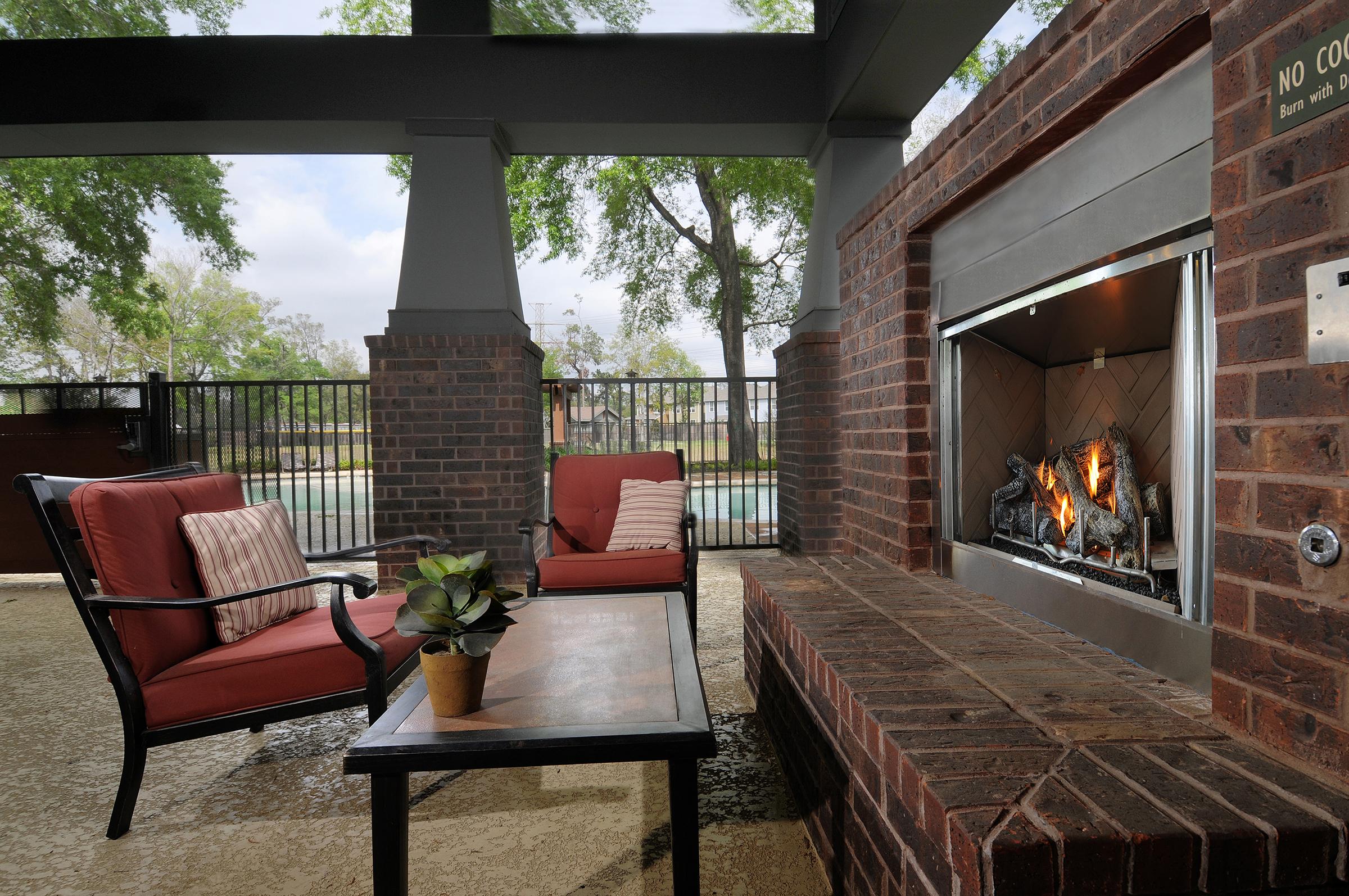chairs and coffee table in front of an outdoor brick fireplace