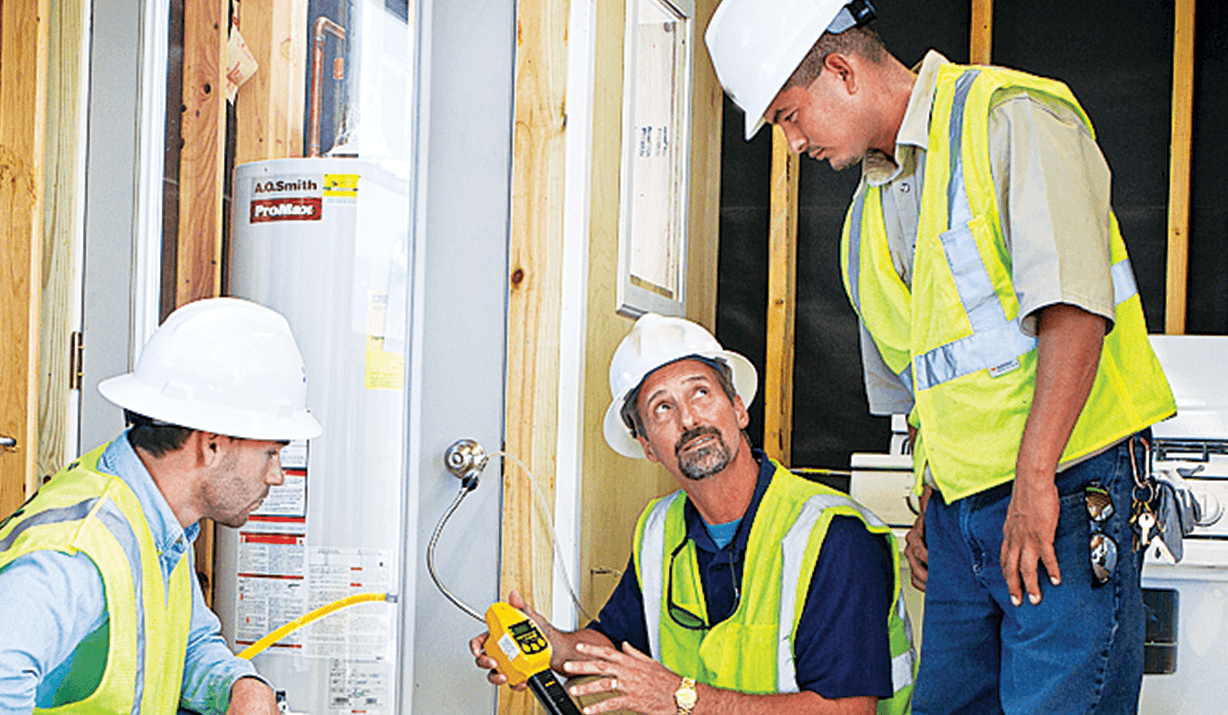 Three utility workers inside a home working on a natural gas water heater